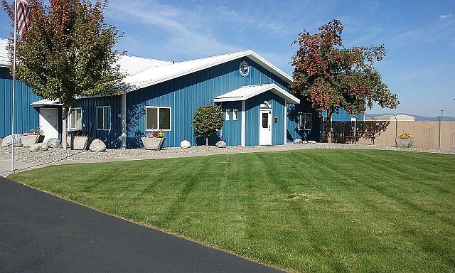 Image of a one story blue building with green lawn